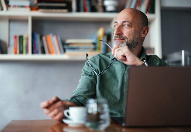Man Working in a Home Office Seated by a Laptop