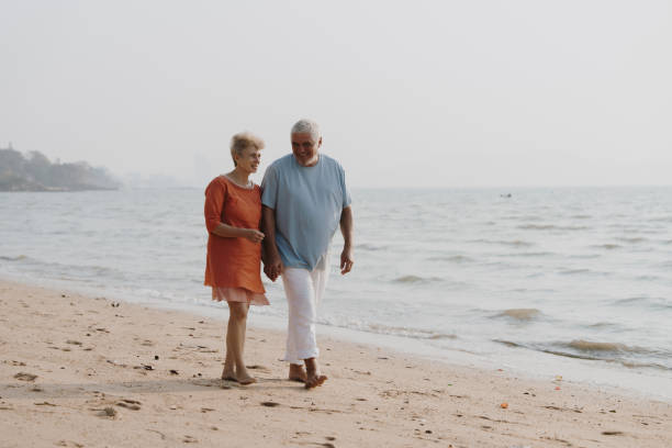 istock Elderly couple drinking sparkling wine at sunset on the beach 2201913222