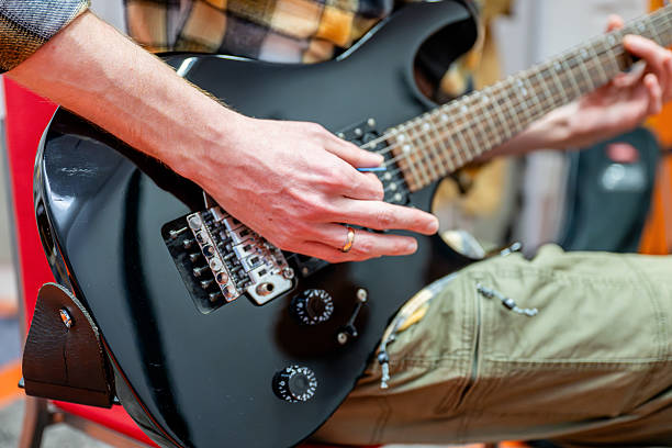 istock Man playing black electric guitar in recording studio 2201914028