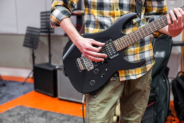 istock Man playing black electric guitar in recording studio 2201914090