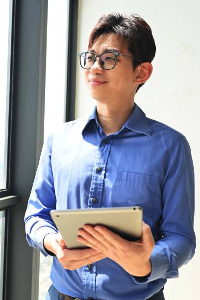 istock Young man standing near window in office 2201919062