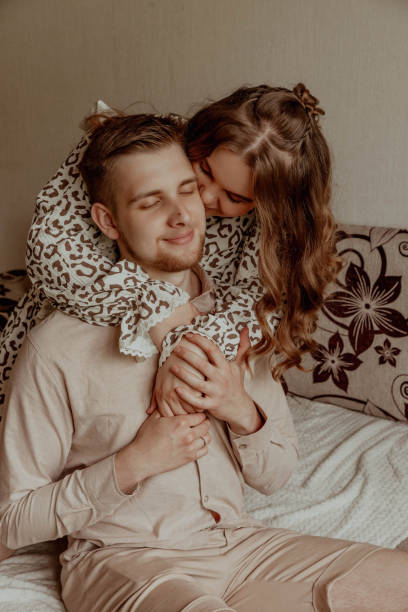istock A woman is comfortably seated on a mans back while resting on a bed 2201919264