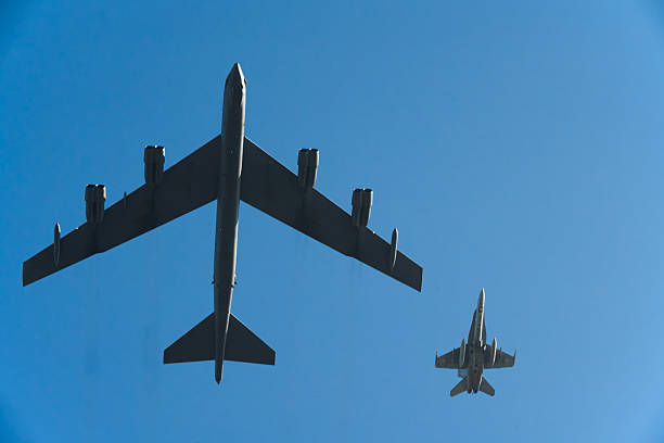istock B-52 Stratofortress and fighter jet flying in formation against a clear blue sky. 2201919507