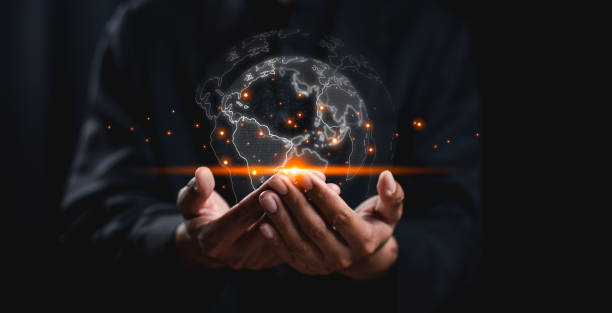 A person holds a glowing, digital globe, surrounded by bright particles, symbolizing global connectivity and innovation against a dark background.