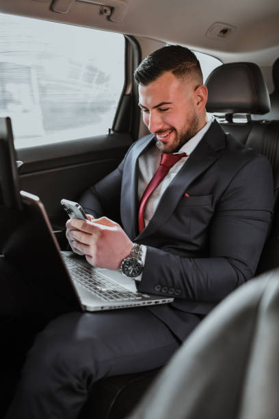 istock Handsome Male CEO Looking Joyful Texting With Wife While Driving to Business Trip 2201920637