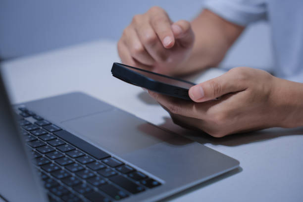 istock Cropped shot of young businessman hand typing on smartphone or laptop computer while working in office room. 2201920819