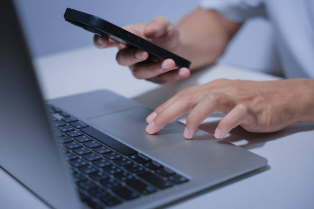 istock Cropped shot of young businessman hand typing on smartphone or laptop computer while working in office room. 2201920863