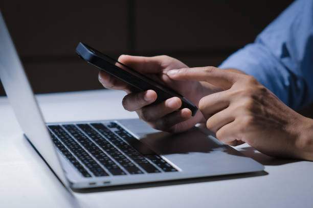 istock Cropped shot of young businessman hand typing on smartphone or laptop computer while working in office room. 2201921047