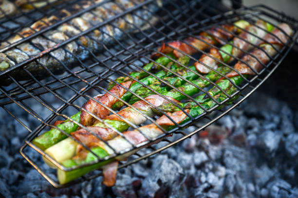 Grilling green asparagus with bacon on grill. Summer time on backyard. Food photography