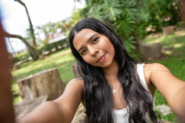istock beautiful young brunette woman taking a selfie in a park 2201922302