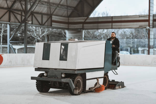 istock Skilled Male Operator Driving Ice Resurfacing Machine Across Ice Rink Preparing for Next Session 2201926999