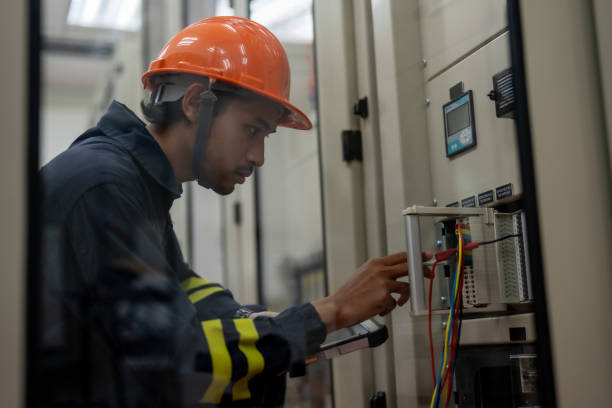 istock technician in orange safety helmet works on electrical equipment, focused on control panel. environment is industrial, showcasing safety and precision in maintenance tasks 2201927069