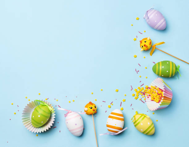 istock Easter decorated colored eggs. Painted eggs, candy bunny, candy chicken, sprinkling on a pastel blue background. Funny children background. Top view. Flat lay. 2201929120