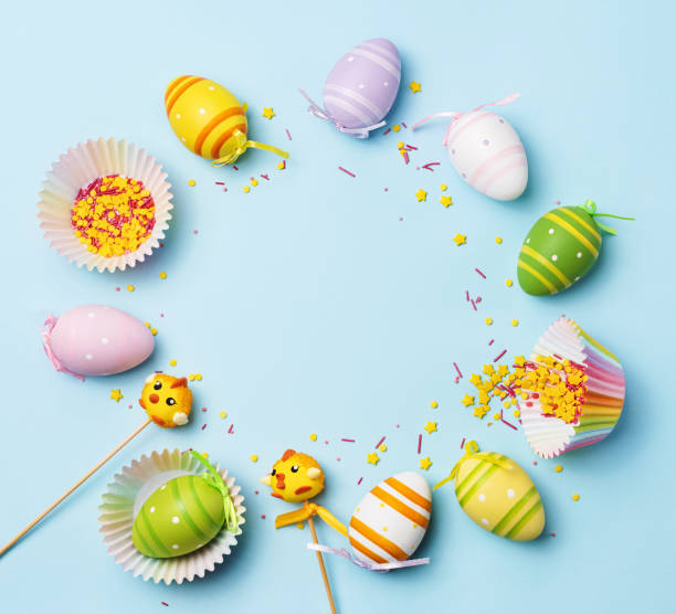 istock Easter decorated colored eggs. Painted eggs, candy bunny, candy chicken, sprinkling on a pastel blue background. Funny children background. Top view. Flat lay. 2201929146