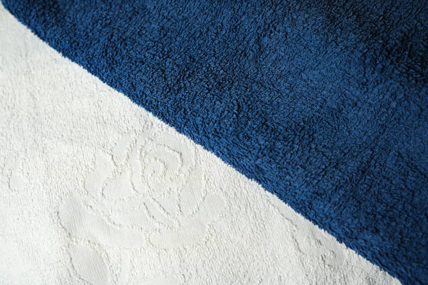 A plush navy towel rests atop a white textured towel in a serene setting.
