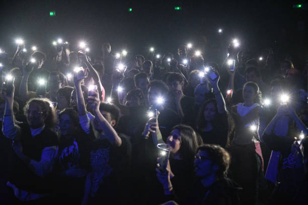 Crowd partying and raising hands at concert while dj performing on stage