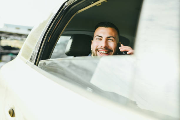 istock Male Enjoying Car Ride Talking on Smart Phone While Admiring Views From Window 2201931582