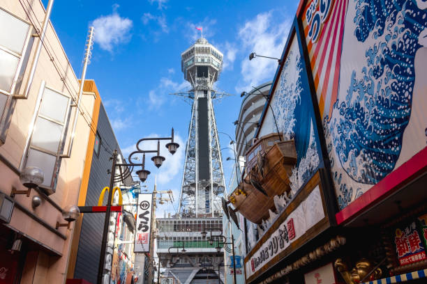 Osaka, Japan - November 11, 2024: The bustling Shinsekai district in Osaka, featuring a McDonald's restaurant alongside local eateries, with the iconic Tsutenkaku Tower rising in the background.