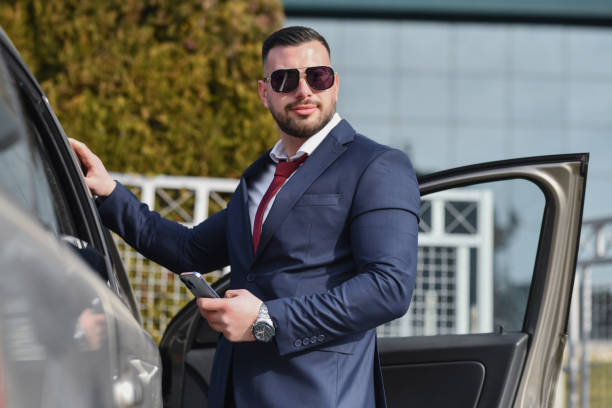 istock Confident Male CEO Getting Out of Car Looking in Distance While Text Messaging 2201932003