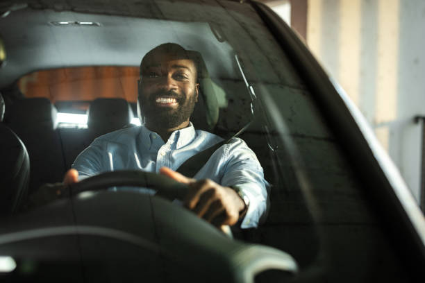 istock Smiling man confidently driving a car in a bright parking garage 2201933122
