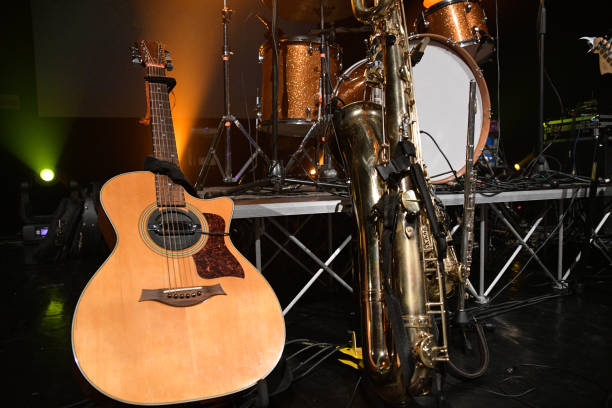 A semi-acoustic guitar and saxophone placed in front of a drum kit on stage, creating a moody and elegant jazz performance scene. The lighting and composition highlight the instruments as the focal point.