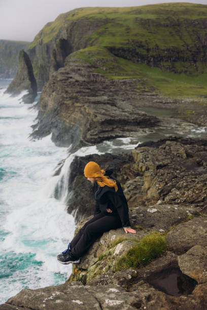 istock Scandinavian Woman Admiring Majestic Cliffs and Ocean on Faroe Islands 2201934607