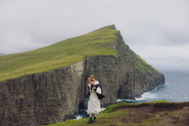 istock Female With Camera Hiking on Faroe Islands Admiring Dramatic Cliffs and Ocean 2201934660