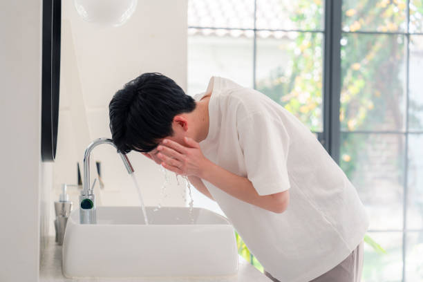 洗面所で顔を洗う若い男 - 早朝覚醒 ストックフォトと画像