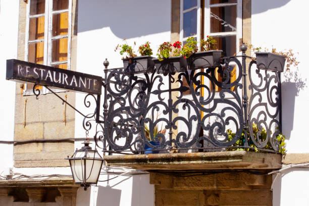 Traditional ancient stone house, cast iron  balcony and restaurant sign, Santiago de Compostela, A Coruña province, Galicia, Spain.