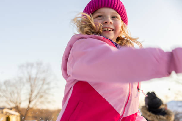 Elementary age girl throws snowball during outdoor play with friends
