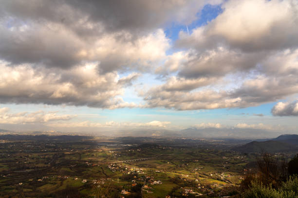 wide view of the countryside and mountains of Ciociaria, under a striking cloudy sky that creates an interesting play of light and shadow on the landscape below