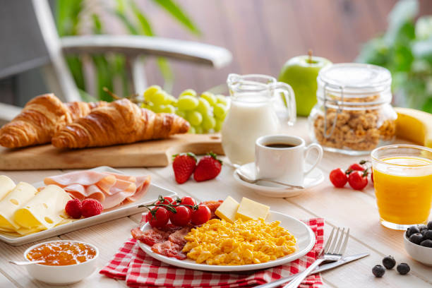 istock Delicious outdoors Continental breakfast table with scrambled eggs plate, fruits, coffee, cheese and ham 2201941694