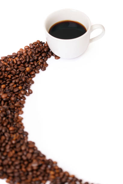 full coffee cup surrounded by spilled roasted whole coffee beans on a white background