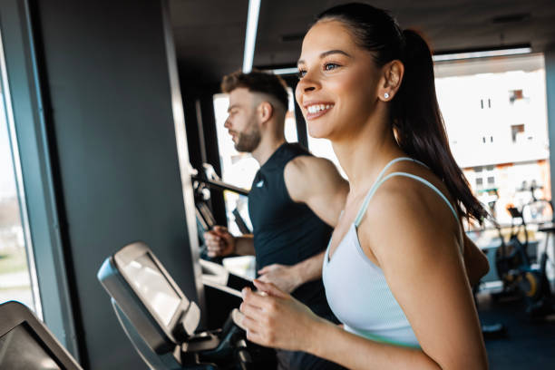 istock Fit Man and Woman Running Side by Side on Treadmills 2201942285