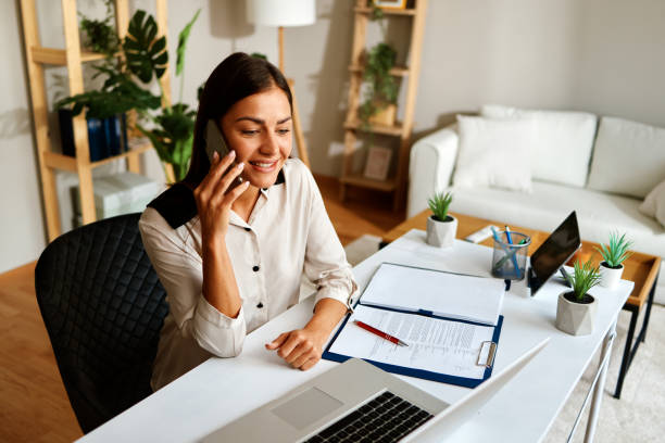 istock Happy businesswoman making a business call while working remotely from her home office 2201946401