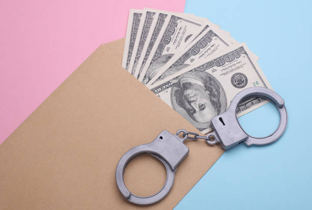 Envelope with money and handcuffs on a pink blue background. Corruption, crime