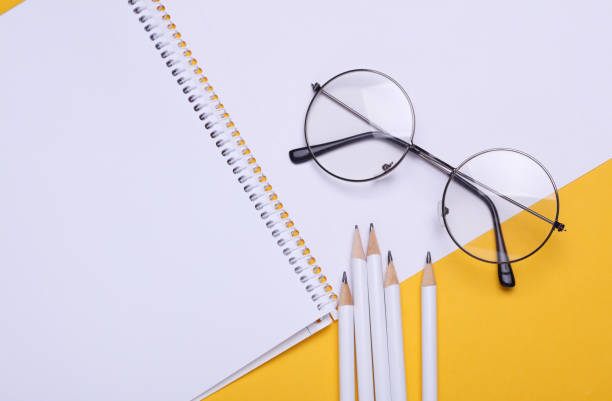 istock Sketchbook with pencils and eyeglasses on yellow background 2201946471