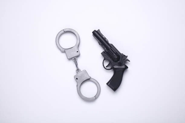 istock Toy gun with handcuffs on white background 2201946499