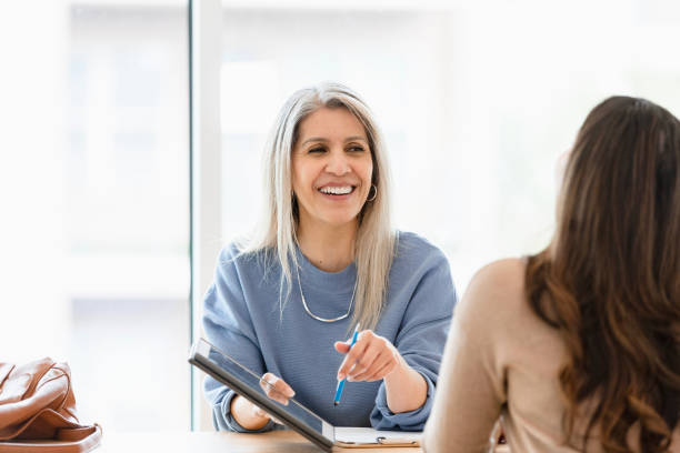 istock Smiling Woman Shows Tablet to Client During Counseling Session 2201948344