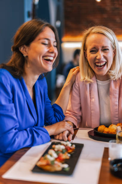 istock Smiling lesbian couple talking to each other at restaurant. 2201949662