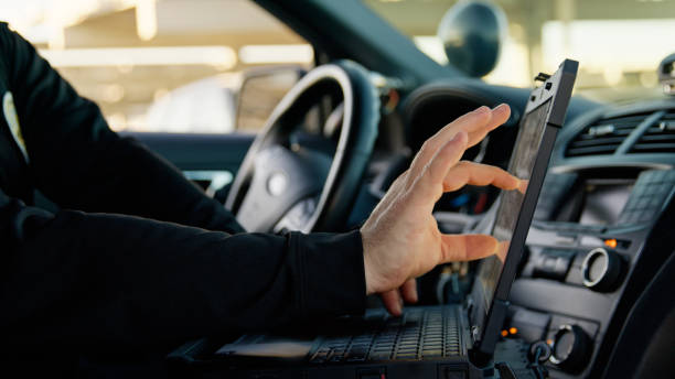 istock Police Officer on Patrol Using Laptop in Car 2201950028