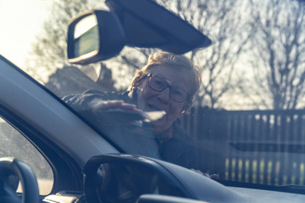 istock Retired woman cleans the windshield car 2201950220