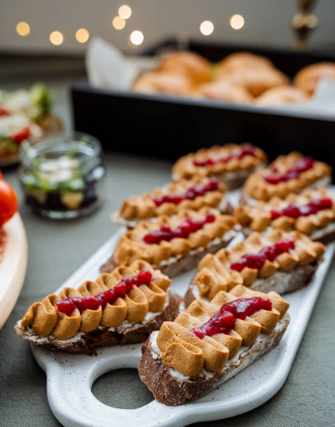 On a table, there is a delightful tray filled with cookies that are generously spread with creamy peanut butter and vibrant raspberry jam. They make for a perfect dessert treat
