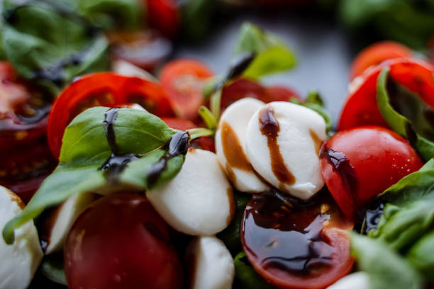 This image showcases a beautifully arranged closeup of a vibrant salad consisting of fresh tomatoes, creamy mozzarella, fragrant basil, all drizzled with delicious balsamic dressing