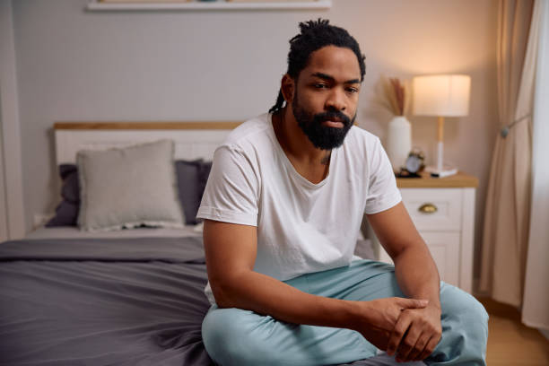 istock Pensive black man thinking of something while sitting in bedroom at home. 2201952088