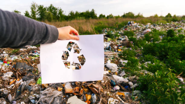 istock Abstract recycling concept featuring a hand holding a recycling logo icon against a garbage background. Symbolizes waste management, eco-friendly practices 2201952482