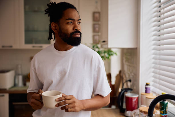 Thoughtful African American man drinking coffee in the morning at home. Copy space.