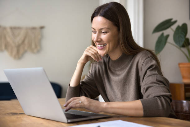 istock Smiling woman using laptop seated at workplace home office 2201952757