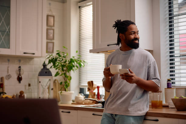 istock Happy black man drinking coffee while texting on mobile phone in the morning. 2201953053