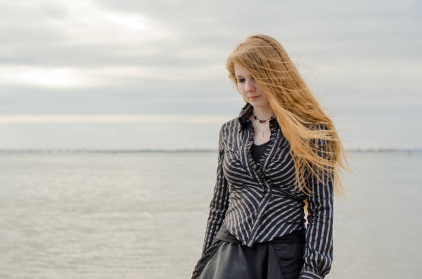 istock Young woman with long hair strolling by tranquil seaside 2201953921